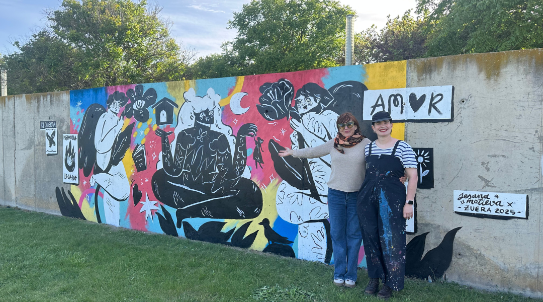 Mural del taller de graffiti – Raíces Vivas Mural colorido realizado en el taller de graffiti del proyecto Raíces Vivas, con dos personas posando delante.